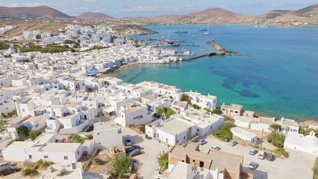 Drone shot of Naoussa, a picturesque coastal town on Paros Island, showcasing its charming harbor, traditional Cycladic architecture, and the turquoise Aegean Sea