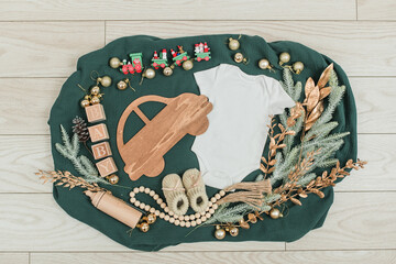 Festive baby announcement setup featuring a baby onesie, a letterboard, and seasonal holiday...