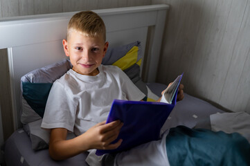 fair-haired teenage boy reading a book before bed