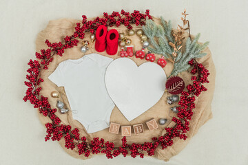 Festive baby announcement setup featuring a baby onesie, a letterboard, and seasonal holiday...