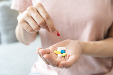 Sick, ill asian young woman, girl hand holding and taking tablet pill capsule, painkiller medicine from stomach pain, head ache, pain for treatment, take drug or vitamin at home, health care concept.