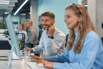 Portrait of call center worker accompanied by his team. Smiling customer support operator at work.