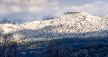 A mountain range covered in snow with a bright sun shining on it