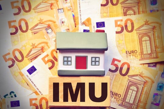 Miniature house with euro banknotes with the sign "Imu" italian tax