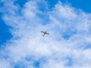 Small ultralight airplane with overhead wing and single propeller flying in sunset sky.