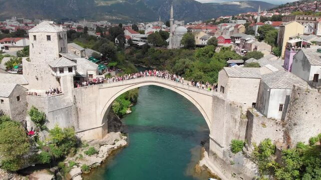 Aerial: drone flying on front of the Stari Most in Mostar in a partially sunny day. Drone circular movement