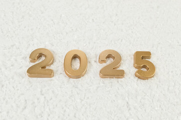 2025 Happy New Year. Top view of gold numbers on white snow background. Copy space, flat lay.