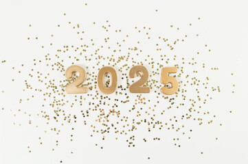 2025 Happy New Year. Top view of gold numbers, gold stars confetti on white background. Copy space, flat lay.