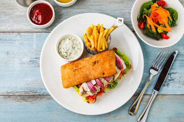 Grilled fish sandwich with red onion. With french fries and sauce