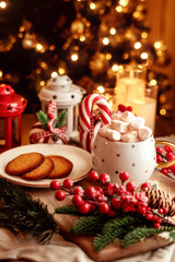 Festive Christmas scene with marshmallows in a cup, candy cane, cookies and cozy holiday decorations. Perfect for Christmas food, holiday vibe, winter warmth, and festive season. 