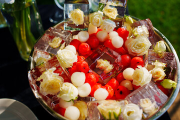 A bowl of ice cubes with frozen flowers and berries. 