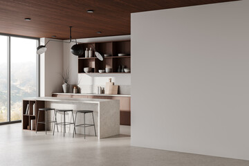 Modern kitchen interior featuring a blank wall, stylish furniture, and natural light from large...