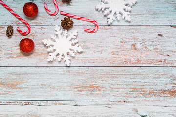 Christmas decorations on a wooden background: Christmas tree balls, branches, snowflakes and candy canes, top view, copyspace