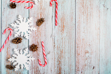 Christmas decorations on a wooden background: Christmas tree balls, branches, snowflakes and candy canes, top view, copyspace