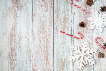 Christmas decorations on a wooden background: Christmas tree balls, branches, snowflakes and candy canes, top view, copyspace