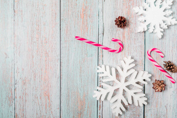 Christmas decorations on a wooden background: Christmas tree balls, branches, snowflakes and candy canes, top view, copyspace