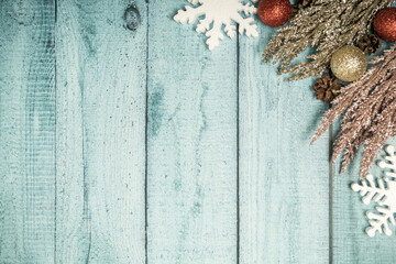 Christmas decorations on a blue wooden background: Christmas tree balls, branches, snowflakes and candy canes, top view, copyspace