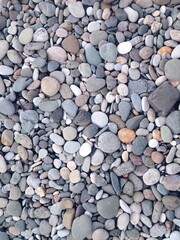 Rock Beach. Round, jagged smooth and textured pebbles, rocks, and stones. Light dark gray slate. Background, landscape. Close up