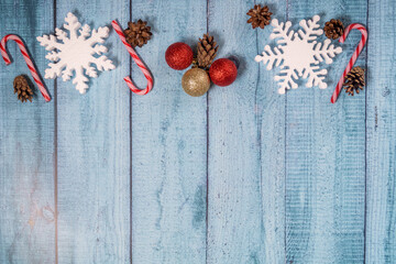 Christmas decorations on a blue wooden background: Christmas tree balls, branches, snowflakes and candy canes, top view, copyspace