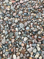 Rock Beach. Round, jagged smooth and textured pebbles, rocks, and stones. Light dark gray slate. Background, landscape. Close up