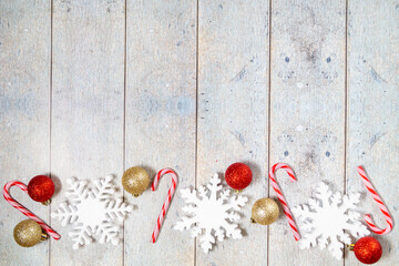 Christmas decorations on a pink wooden background: balls, branches, snowflakes and candy canes, top view, copyspace