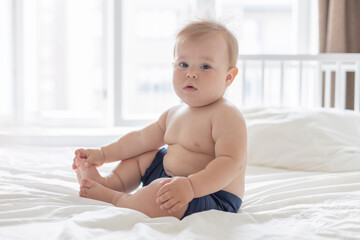 Cute 8-month-old baby with a on a white bed