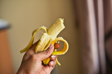 Peeled banana on male asian hand with blurry background