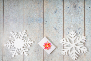White decorative snowflakes and giftbox on a wooden background, copy space