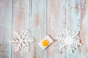 White decorative snowflakes and giftbox on a wooden background, copy space