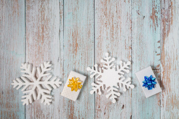 White decorative snowflakes and giftbox on a wooden background, copy space
