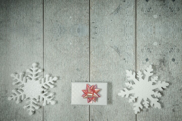 White decorative snowflakes and giftbox on white wooden background, copy space