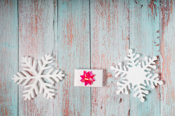 White decorative snowflakes and giftbox on white wooden background, copy space