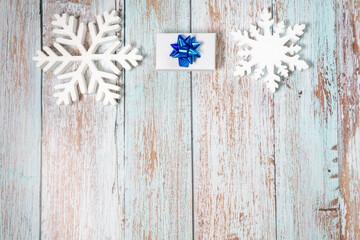 White decorative snowflakes and giftbox on white wooden background, copy space