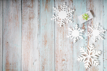 White decorative snowflakes and giftbox on white wooden background, copy space
