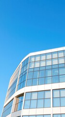 Modern office building with sleek glass windows against a clear blue sky, architecture, glass
