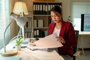 Asian businesswoman working using PC computer in modern office Freelance female employee reports online marketing Analyze reports from data files startup business idea working overtime.