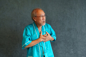 Elderly man with pain and illness standing on black wall background