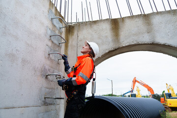 A female engineer inspects the inside of a large concrete pipe. Workers build a pipeline to transport oil, natural gas and fuels in industrial plants.