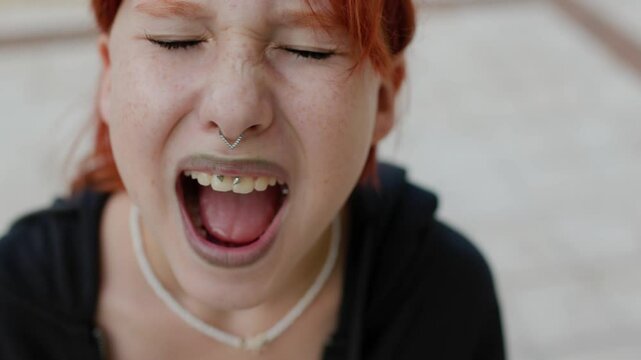 Upset girl screaming, teenager with facial piercing. shock and emotional breakdown, depression.