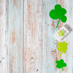 Green four leaf clovers and giftbox on white wooden background top view. Happy St. Patrick's Day...