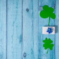 Green four leaf clovers and giftbox on white wooden background top view. Happy St. Patrick's Day...