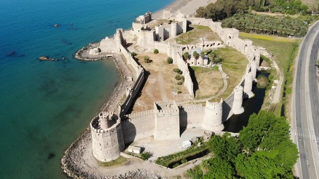 Picturesque drone view of remains of medieval castle Mamure Kalesi in Bozdogan village on coast near turquoise waters of Mediterranean Sea on sunny spring day, Turkey