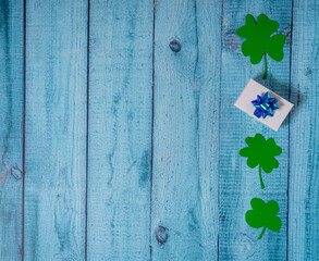 Green four leaf clovers and giftbox on white wooden background top view. Happy St. Patrick's Day greetings © Mikhail Taratonov
