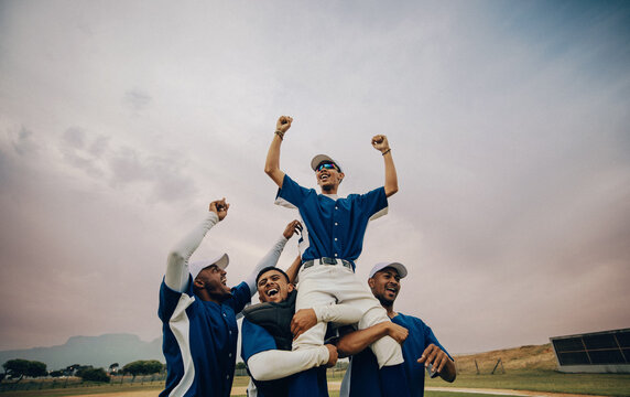 Baseball team celebrates as team members triumphantly lift a player into the air