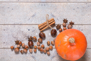 Pumpkin, chestnuts, anise, cinnamon, hazelnuts on a wooden background. Top view, copy space