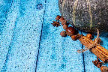 Pumpkin, chestnuts, anise, cinnamon, hazelnuts on a blue wooden background. Top view, copy space