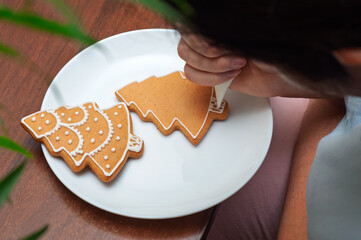 Decorating homemade gingerbread cookies in the shape of Christmas trees.