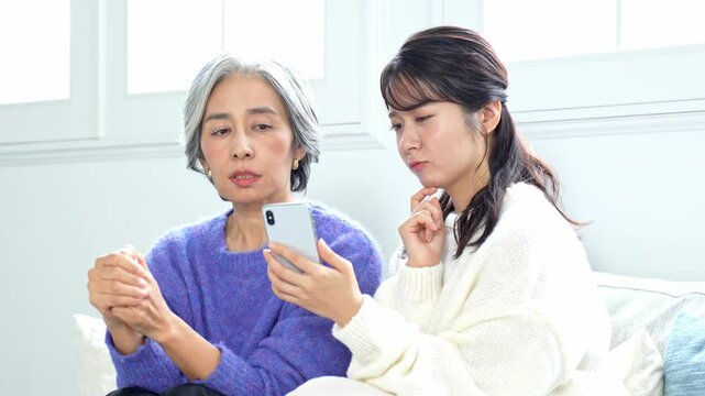 携帯を見て不安げな表情を見せる二人