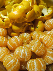 Peeled tangerines and tangerine peel in a metal cup. Tangerine background for text. Citrus fruits. Juicy mandarin close-up.