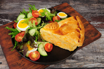 Shortcrust pastry cheese and potato filled pie slice with fresh egg salad meal